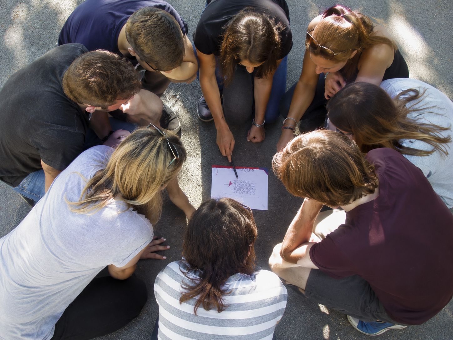 Gruppe arbeitet draußen im urbanen Raum mit Karten und Symbolen.